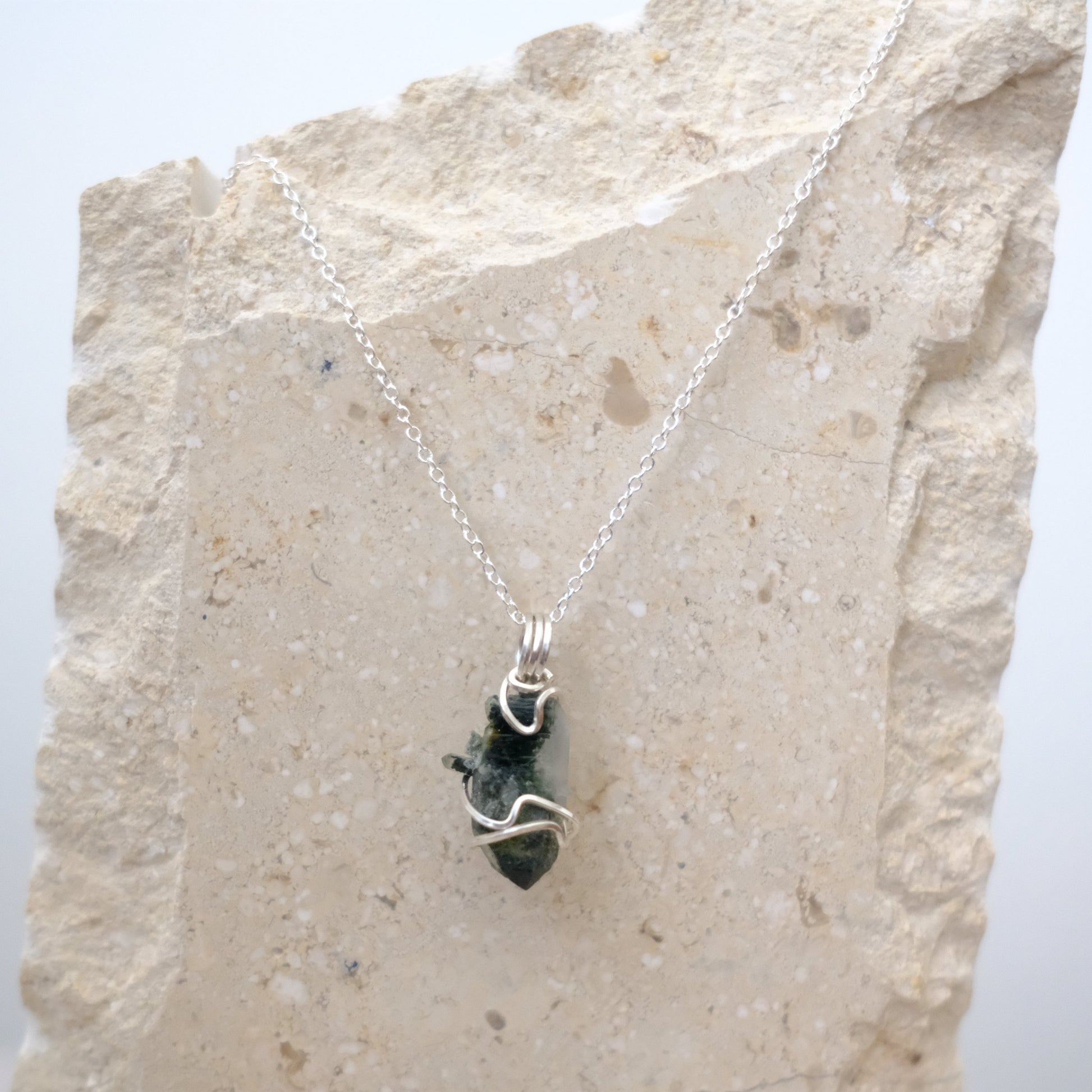 Close-up of Green Phantom Quartz crystal pendant with silver wire wrapping