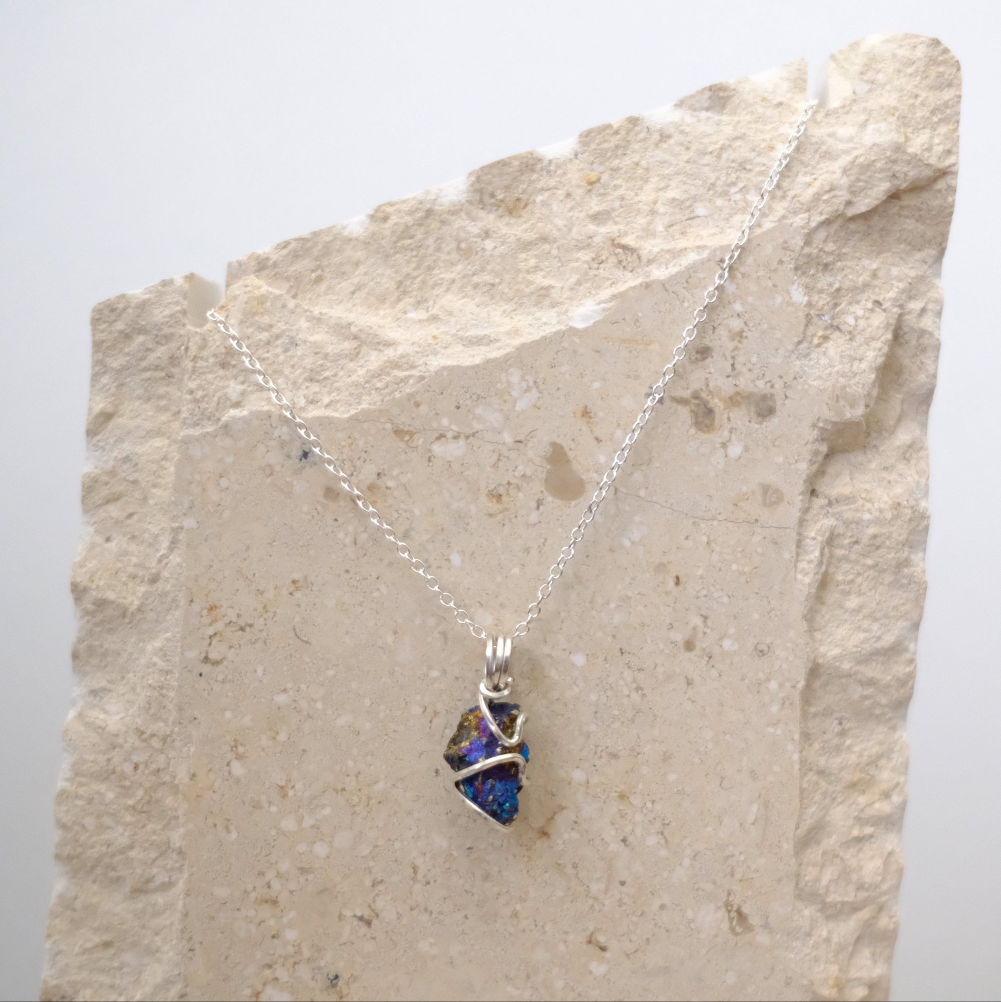 Close-up of iridescent Chalcopyrite pendant with silver wire wrapping
