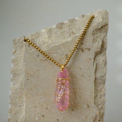 Close-up of rose aura quartz crystal wrapped in gold plating, showing shimmering pink rainbow details and artisan craftsmanship.