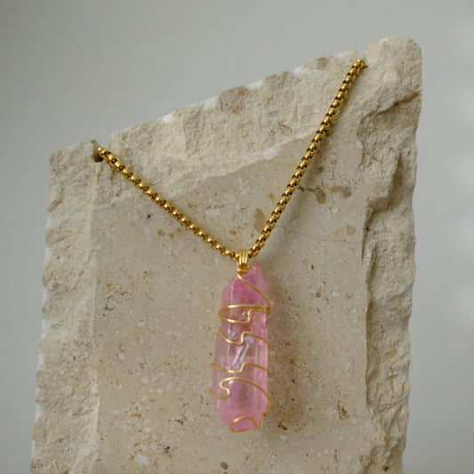 Close-up of rose aura quartz crystal wrapped in gold plating, showing shimmering pink rainbow details and artisan craftsmanship.