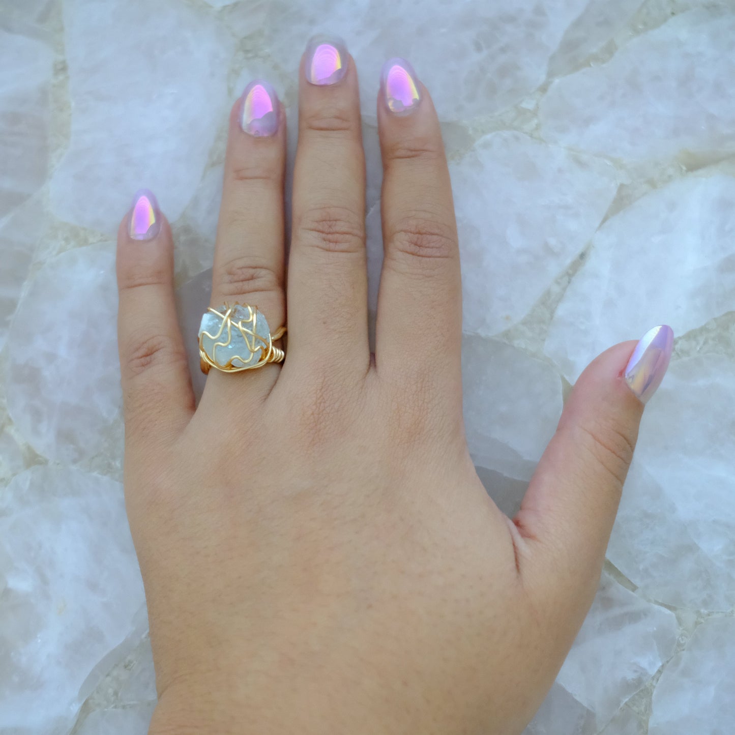 Hand wearing handmade gold plated aquamarine ring with natural gemstone and adjustable band.